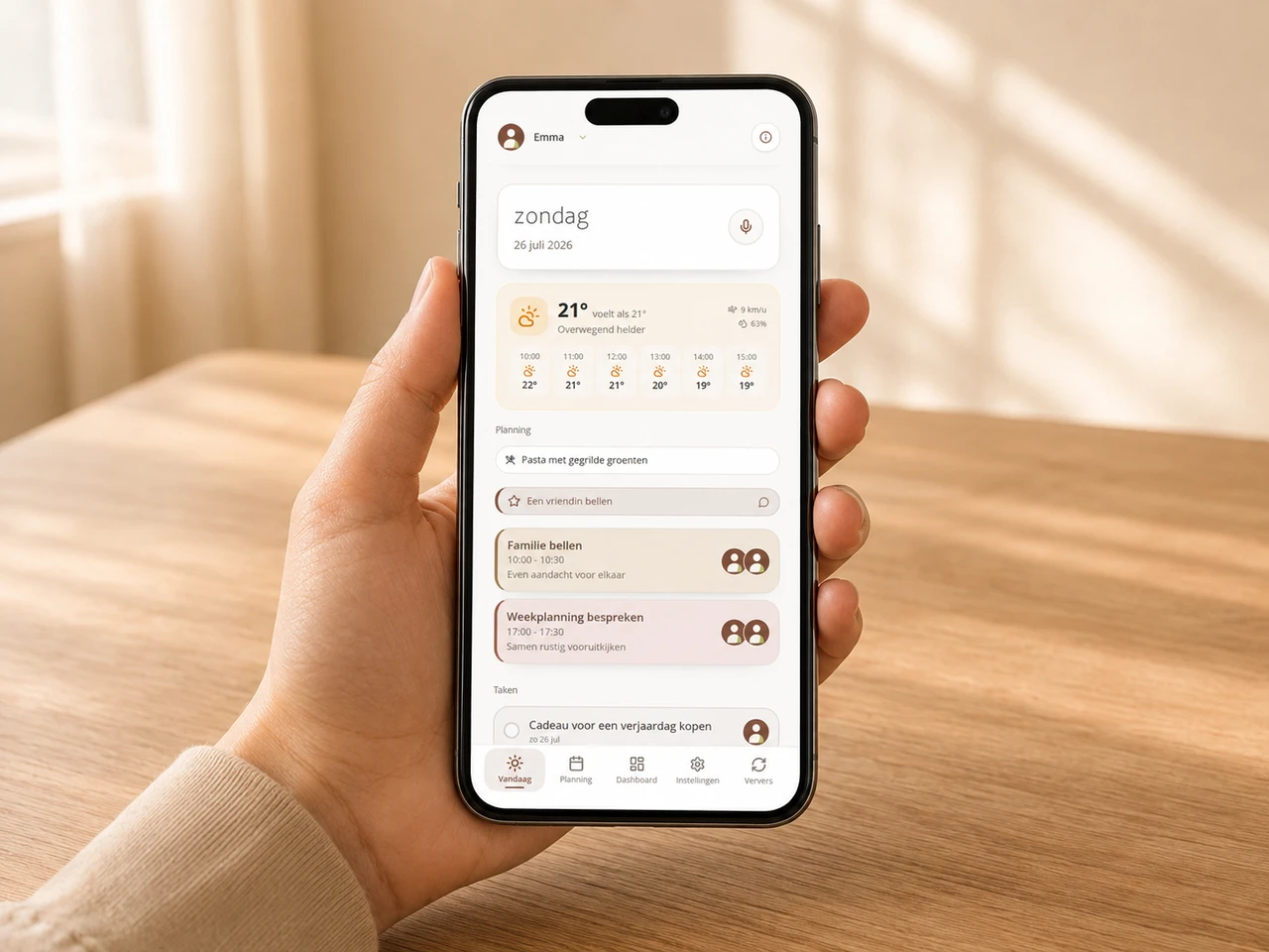 PlanItTogether Vandaag-scherm op een telefoon in een hand boven een houten tafel