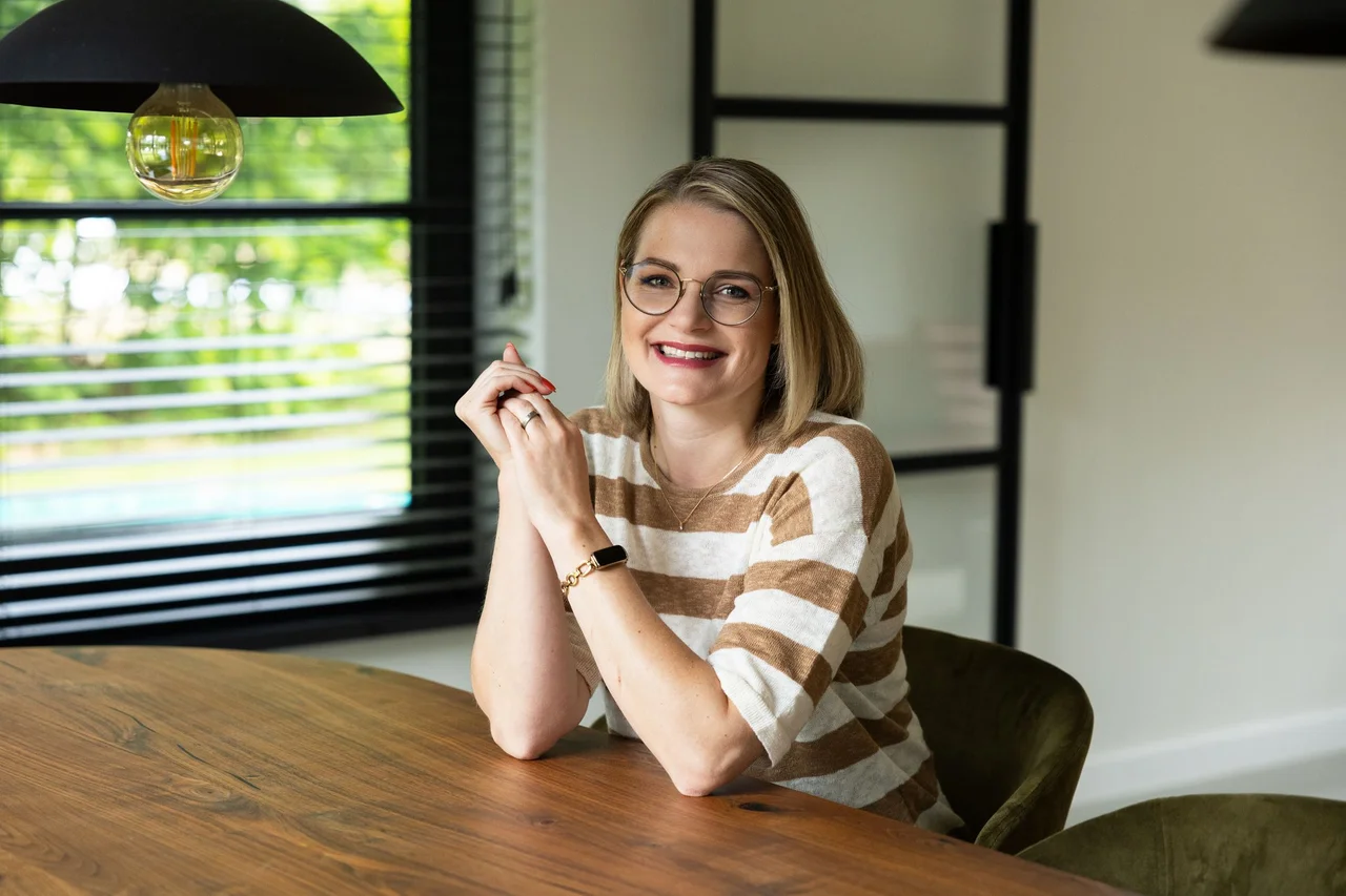 Laurien aan de houten tafel, klaar voor een persoonlijk gesprek